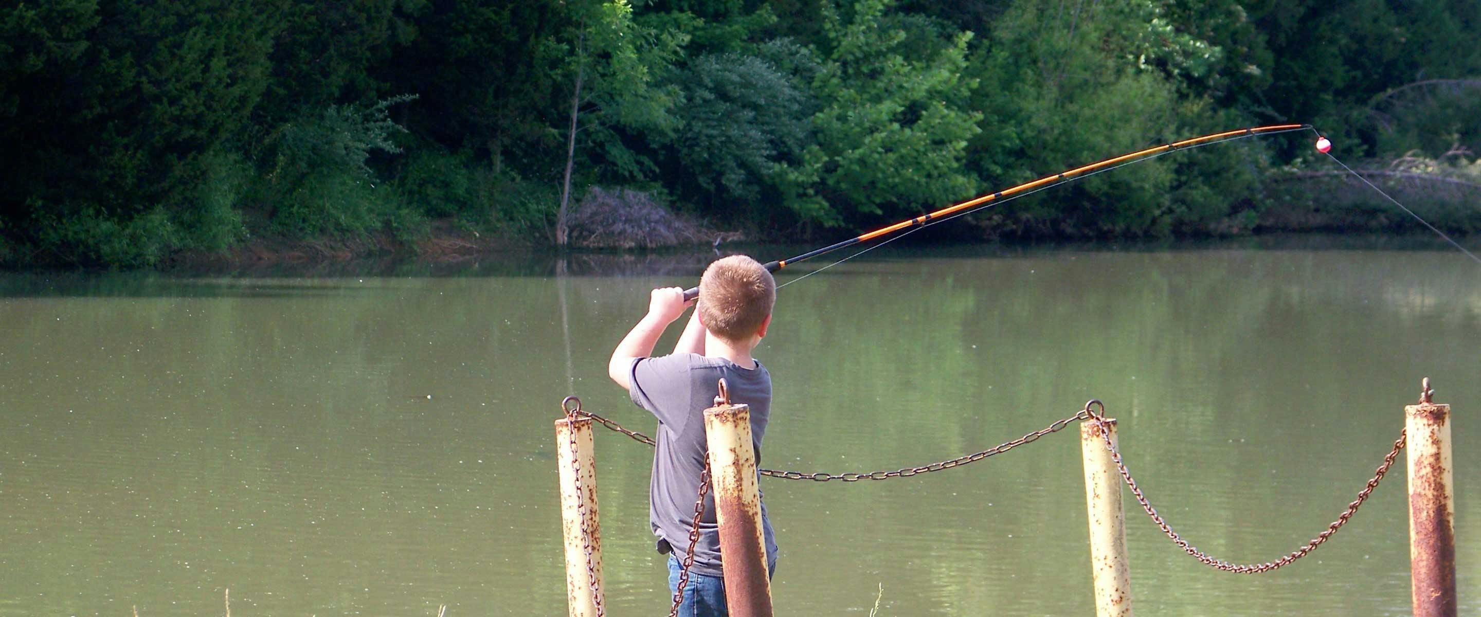 boy casting out into water to fish
