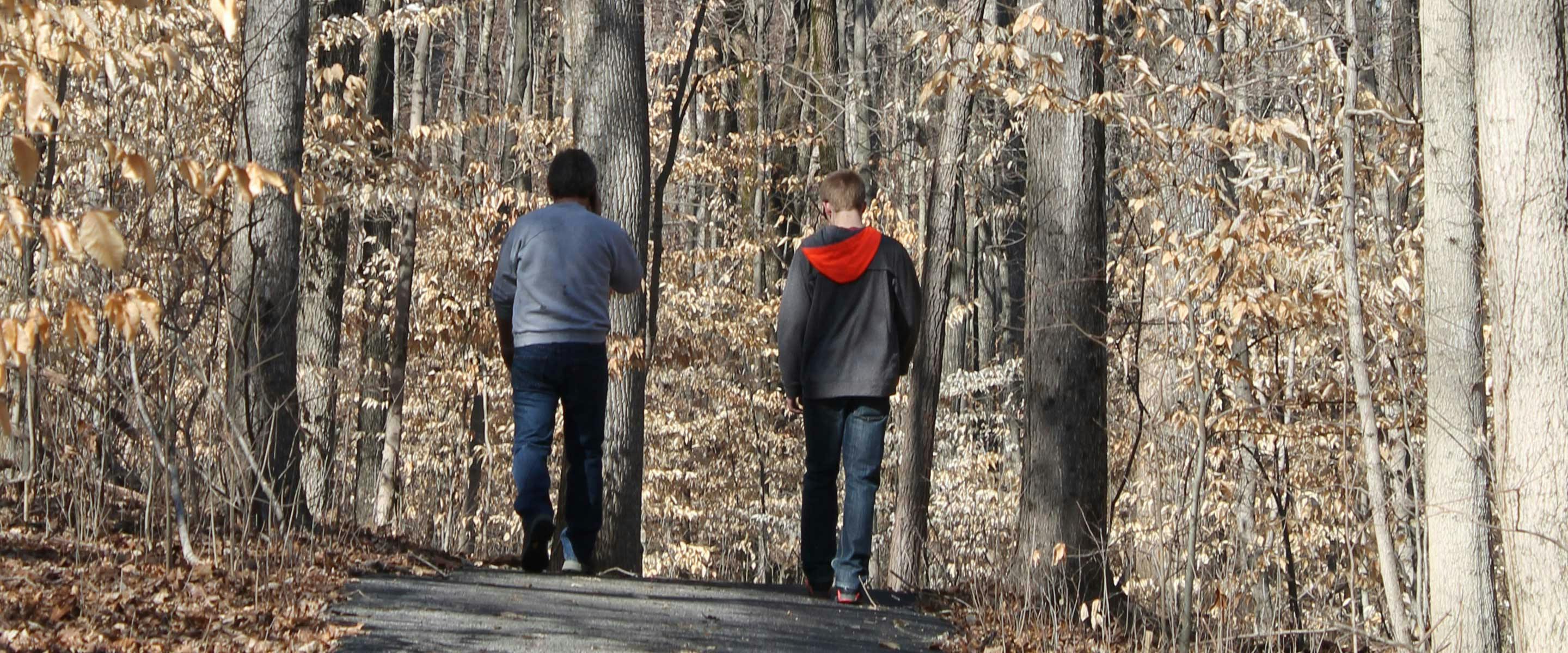two men walking trail in the fall with leaves falling